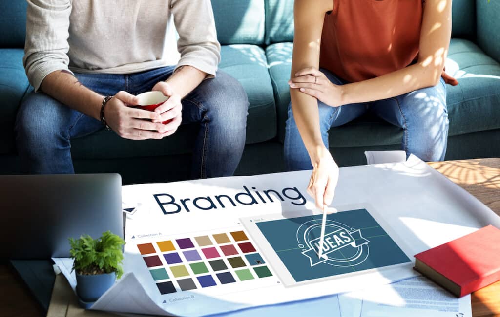 Hands arranging branding materials including logos, colors, and typography on a workspace